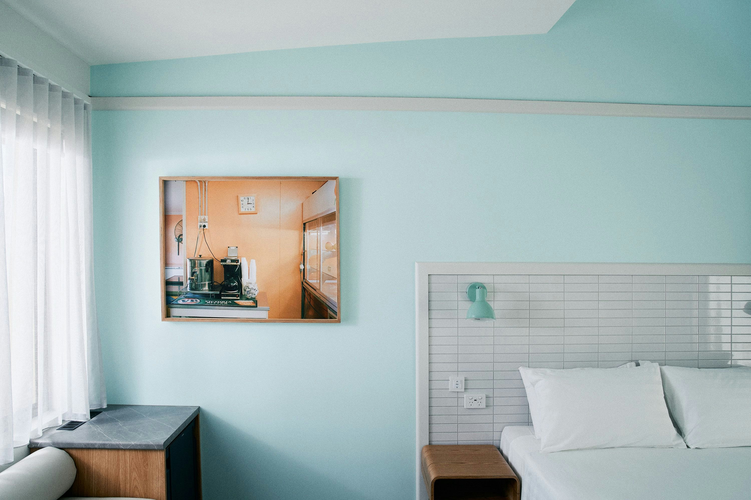 a motel room with a turquoise wall and a retro painting